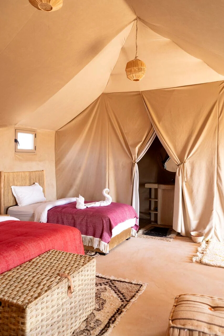 Inside a tent showing the beds and the draped doorway leading to the private ensuite bathroom