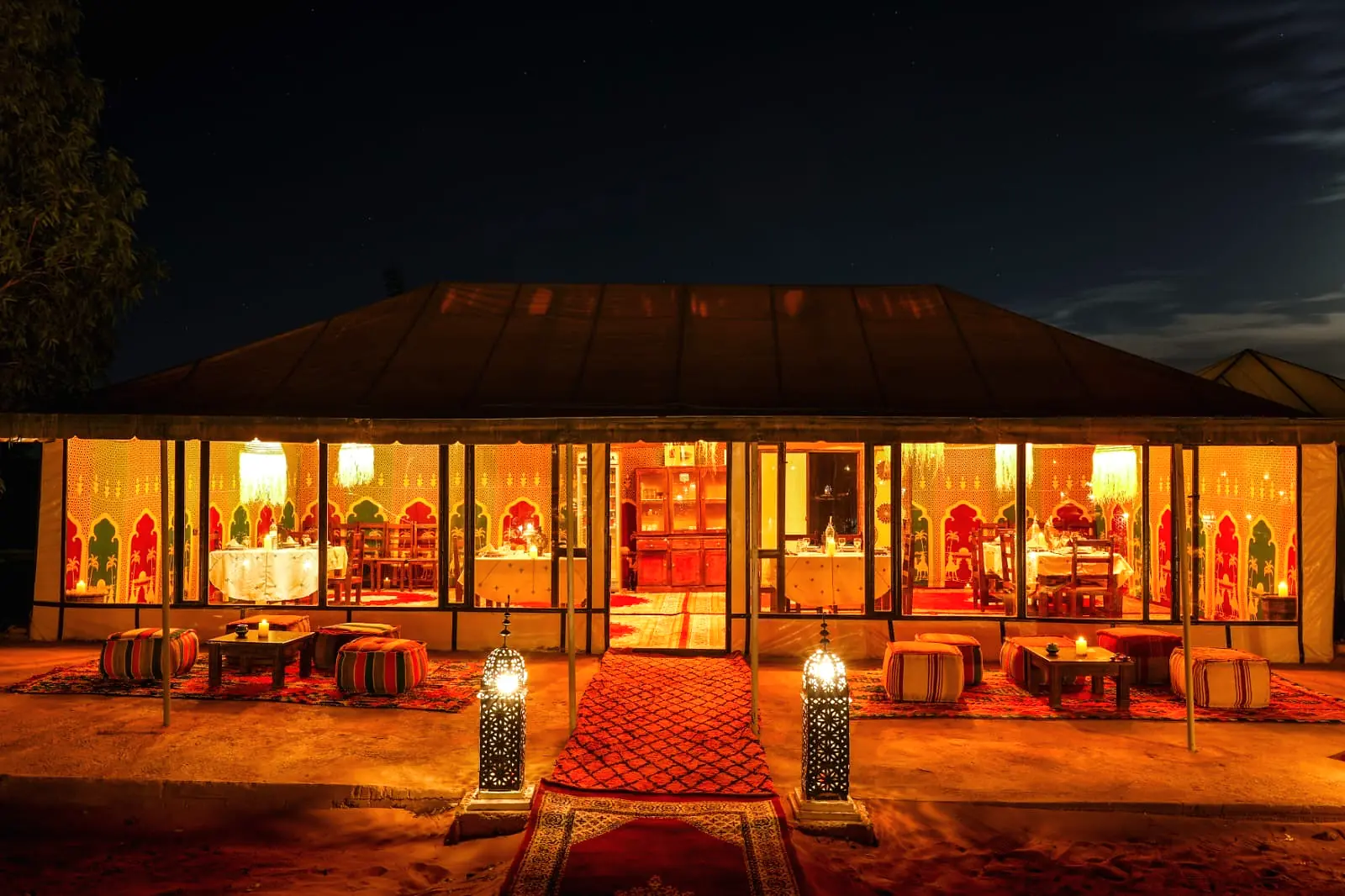 Exterior of the dining tent glowing with warm light after dark at the desert camp