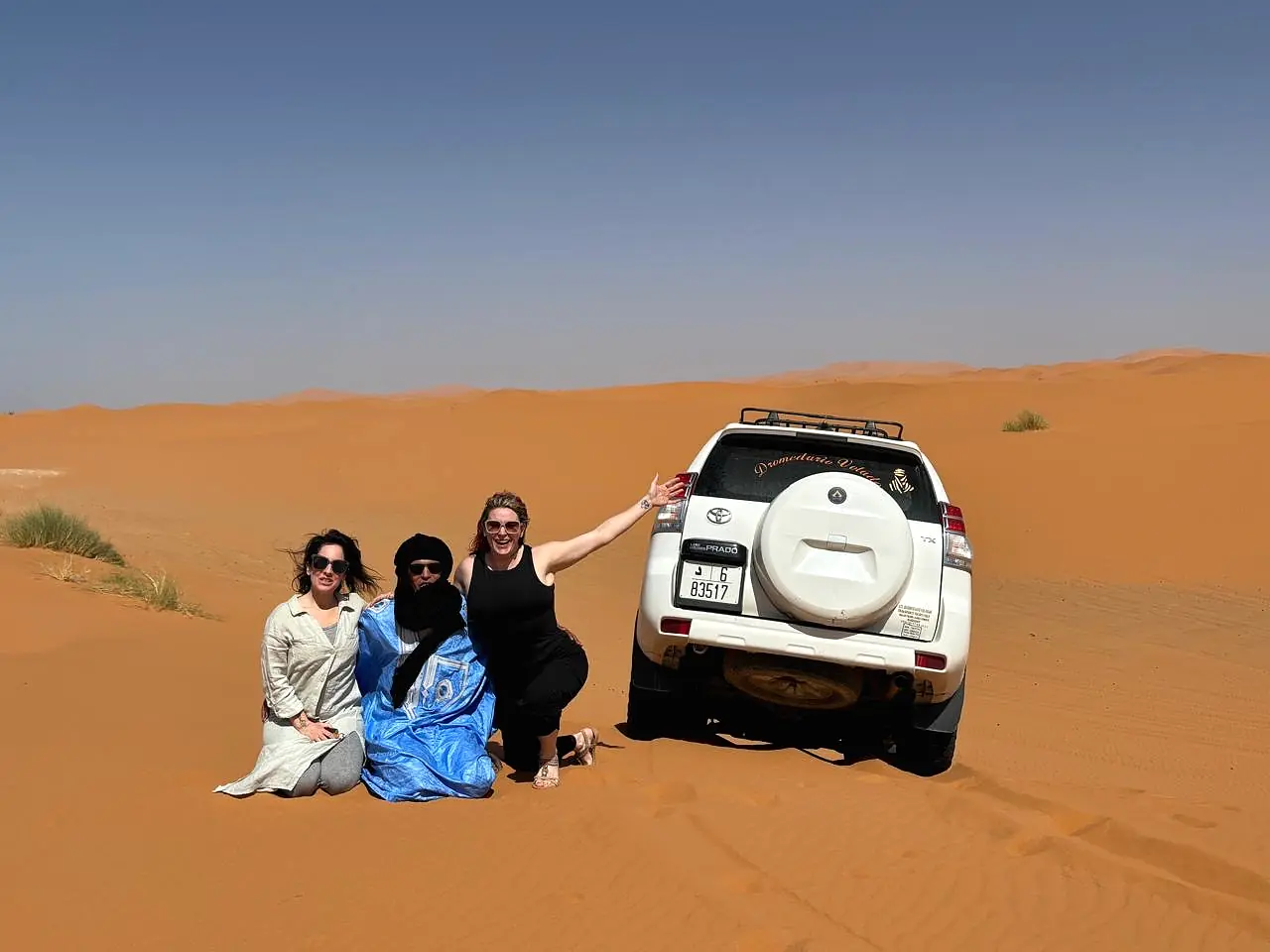 Mohamed and two guests beside the private Toyota 4x4 on the orange dunes of Erg Chebbi