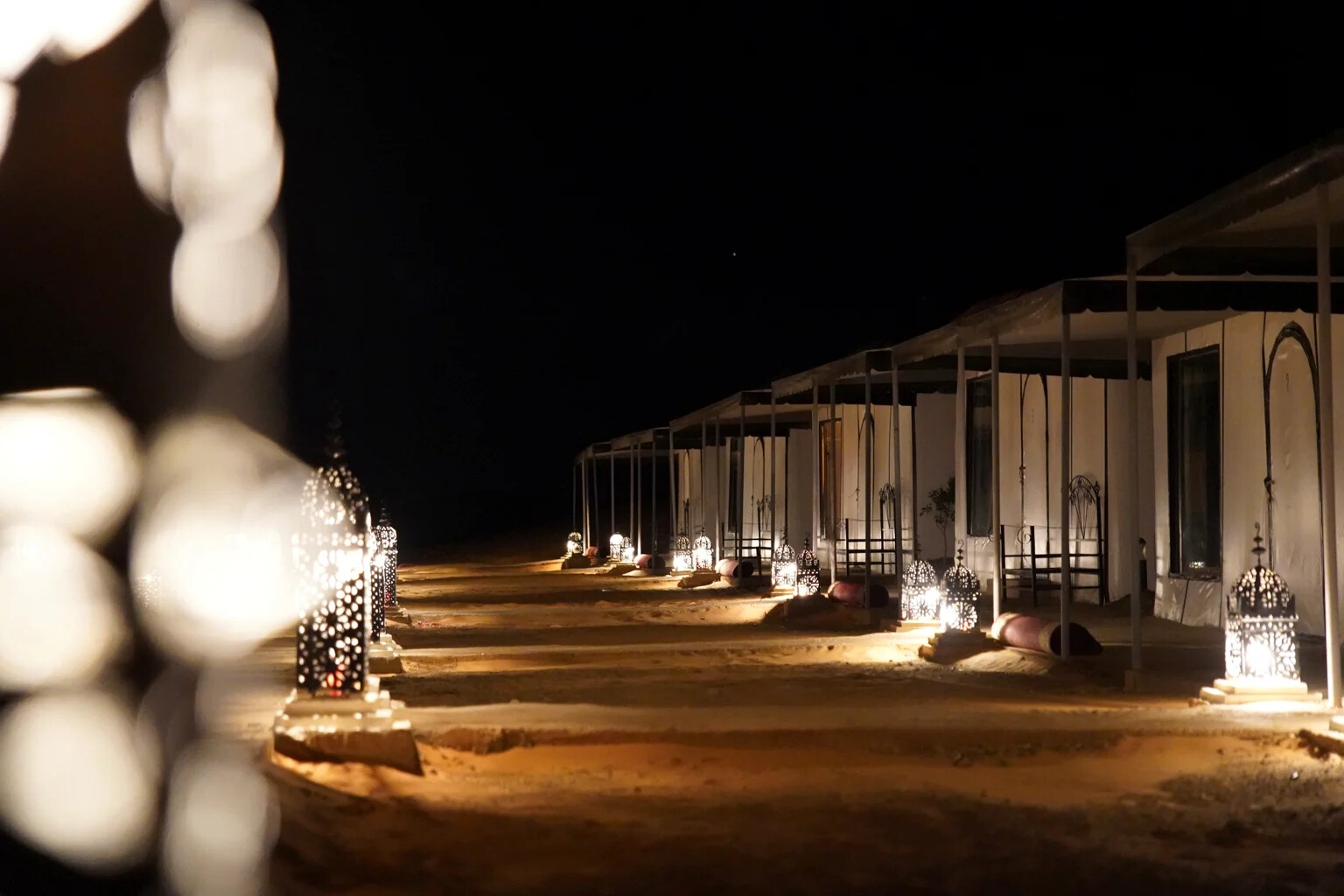 Close view of the camp tents at night glowing beside ornate Moroccan lanterns