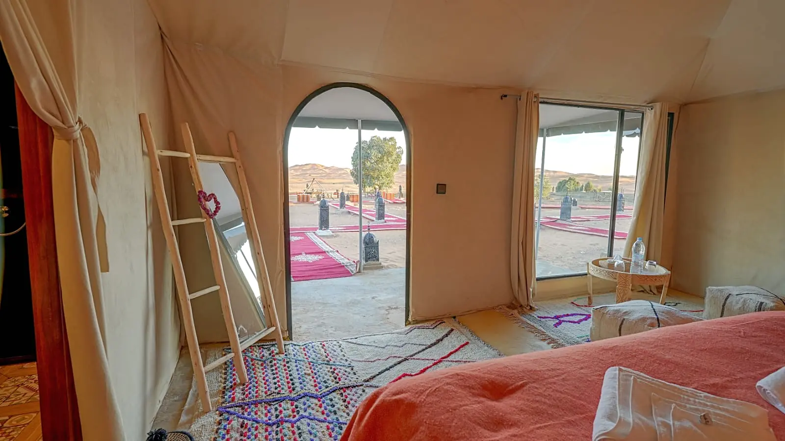 Tent interior looking through wide windows towards the camp walkways and the dunes beyond
