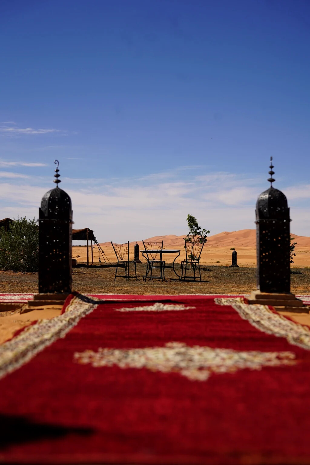 View from the camp's red carpet path towards a tea table and the Erg Chebbi dunes beyond