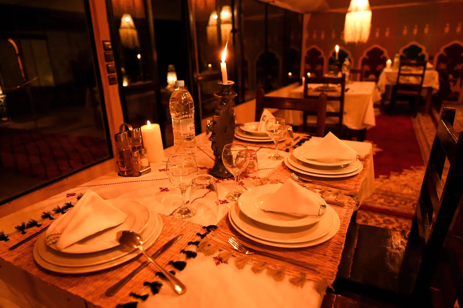 Dinner table inside the dining tent set with linen and lit by a single candle