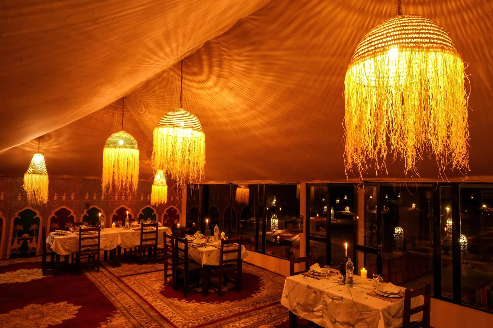 Interior of the dining tent with large woven lanterns hanging above the tables
