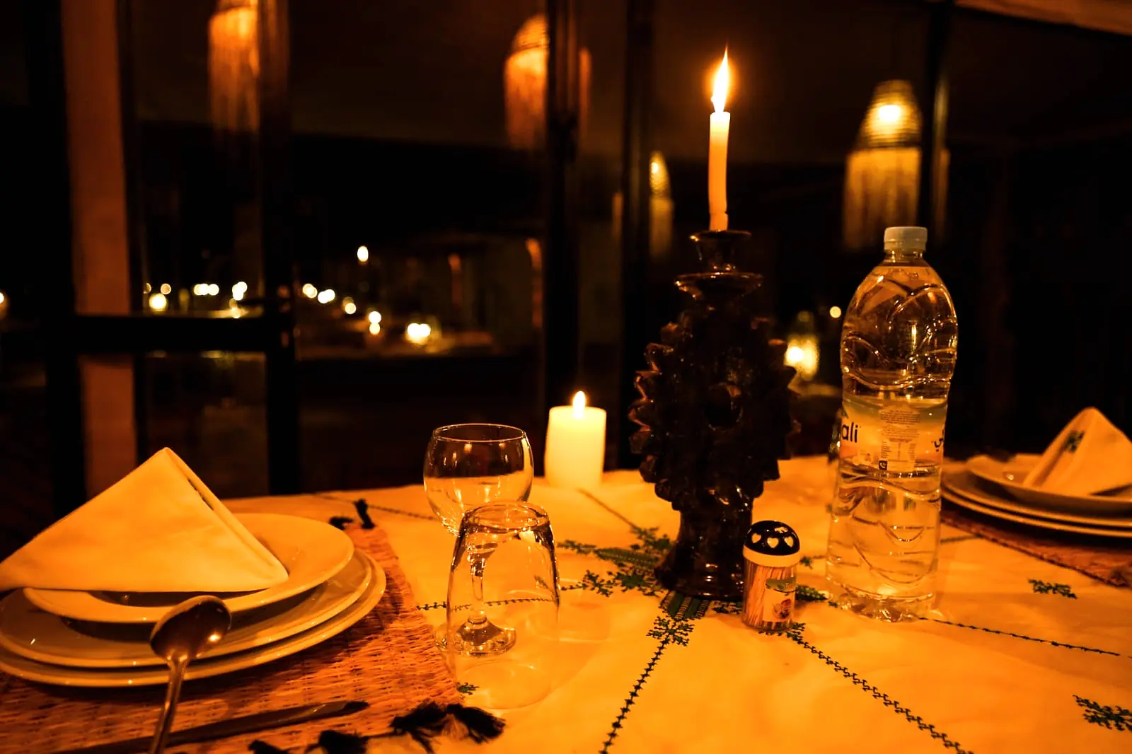 Close view of a dinner place setting with candle, glassware and water at the camp dining table